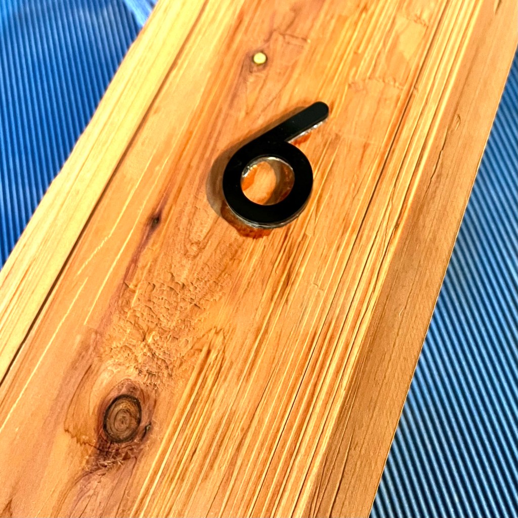 Rough cut wood with an acrylic number on it