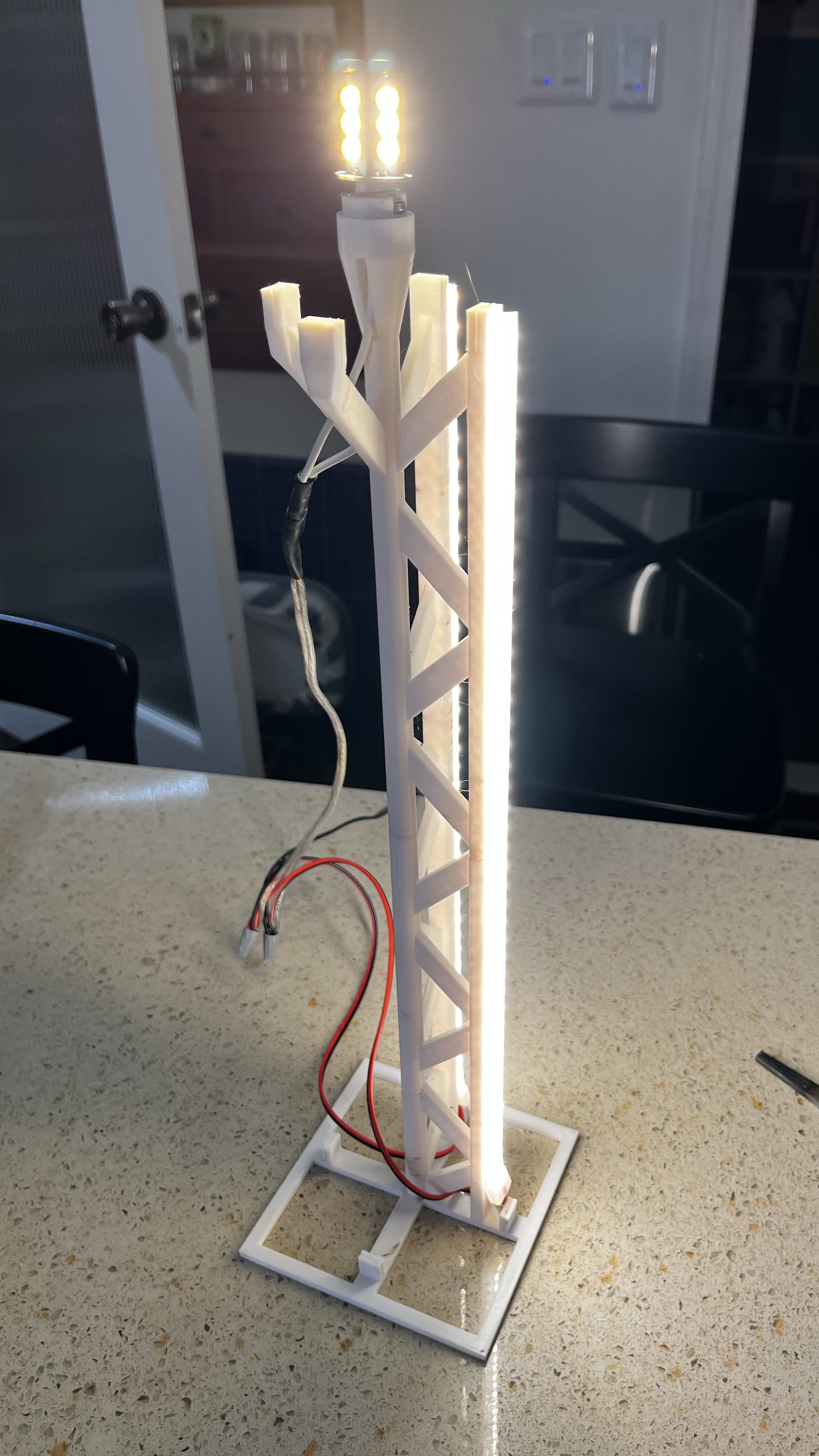 3d printed internal structure with bulb at the top and led strip running down the side, lit up.