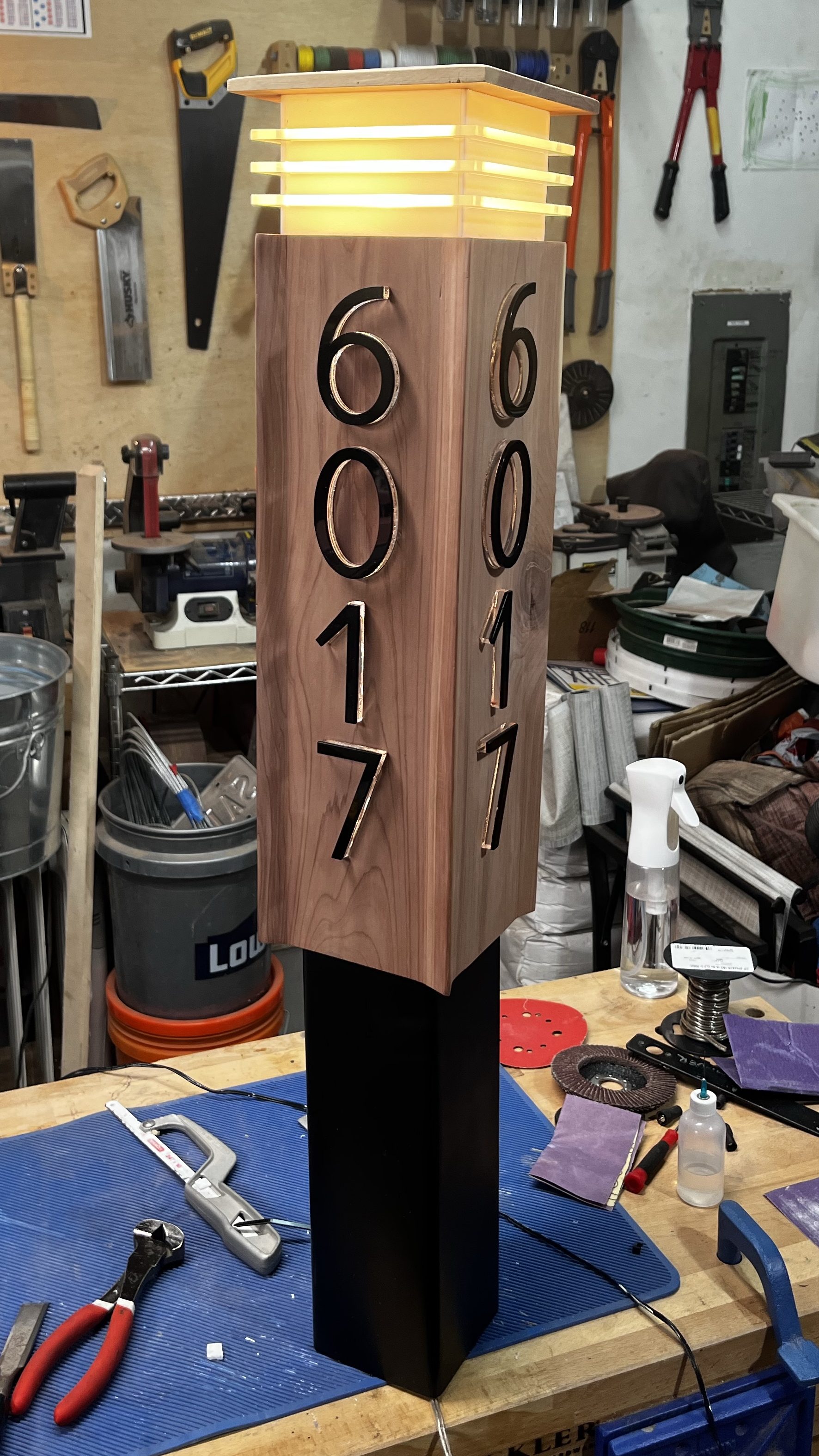 Completed lamp sitting on base and lit up for testing on workbench.